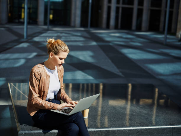 istock Stylish executive woman using laptop outside 1017557074