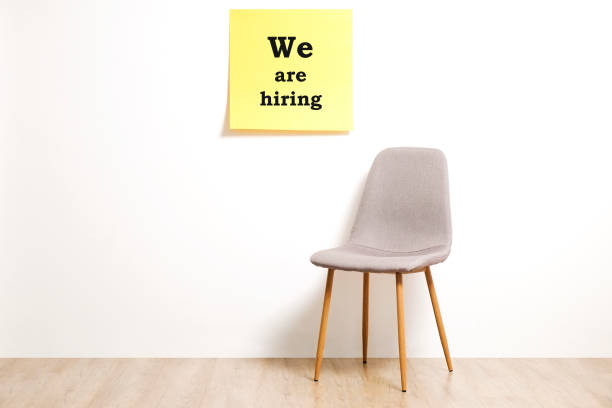 istock Head hunting help wanted poster concept. Minimalistic composition with chair and blank copy space wall. 1017577184
