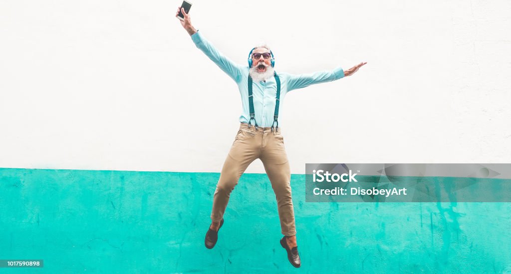 Senior Hombre loco saltando y escuchar música al aire libre - hombre maduro feliz celebrando y bailando fuera - concepto alegre estilo de vida en la tercera edad - foco en lo - Foto de stock de Tercera edad libre de derechos