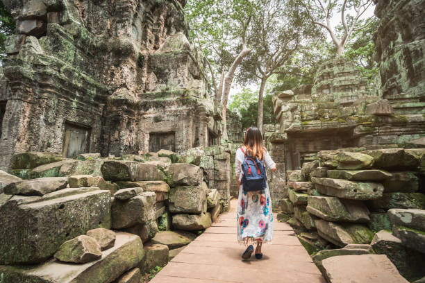 młoda kobieta podróżniczka odwiedzająca świątynię ta prohm w kompleksie angkor wat, dziedzictwo architektury khmerskiej w siem reap, kambodża - cambodia zdjęcia i obrazy z banku zdjęć