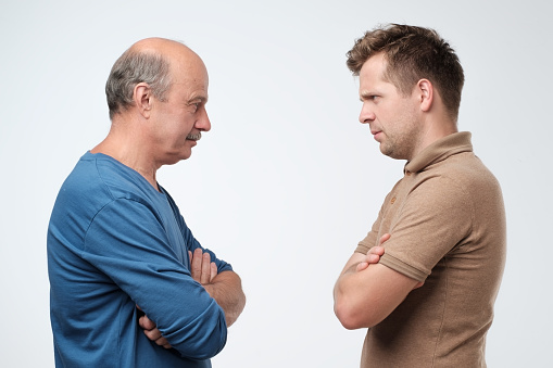 Mature father and son looking on each other face to face. They quarreled. To make claims and reproaches