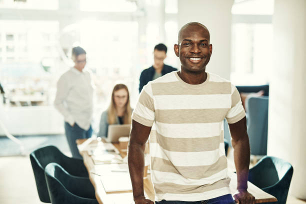 istock Young African designer smiling with colleagues working in the background 1017602872