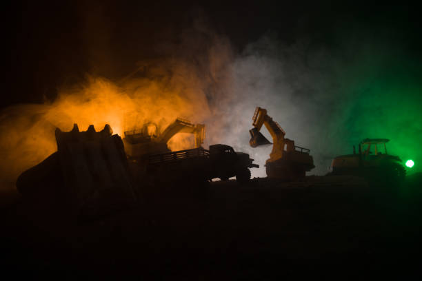 istock Construction site on a city street. A yellow digger excavator parked during the night on a construction site. Industrial concept table decoration on dark foggy toned background 1017607648