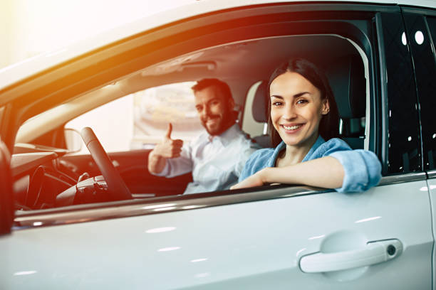 Young beautiful couple buying a new car in dealership stock photo