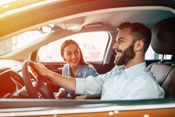 junge schöne paar beim kauf eines neuwagens im autohaus - driving new car driver stock-fotos und bilder