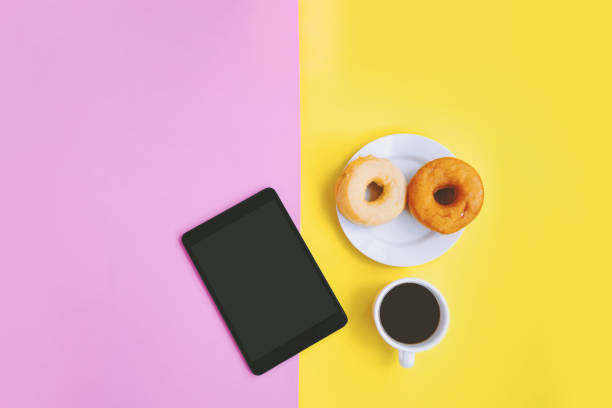istock Coffee break concept. A cup of coffee, donuts and tablet on pastel background with copy space 1017625722