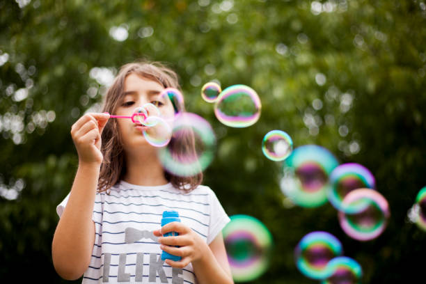 fille souffle des bulles de savon - bubble child bubble wand blowing photos et images de collection