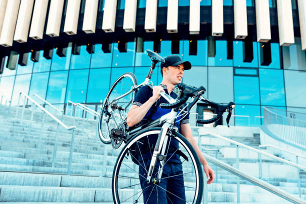istock Man walks on stairs outside and holds on to his commuter bicycle 1017631438