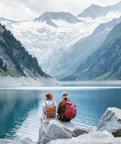 Travelers couple look at the mountain lake. Travel and active life concept with team. Adventure and travel in the mountains region in the Austria stock photo