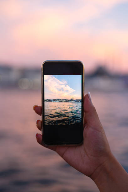 istock Woman taking a sunset photo by phone 1017631472