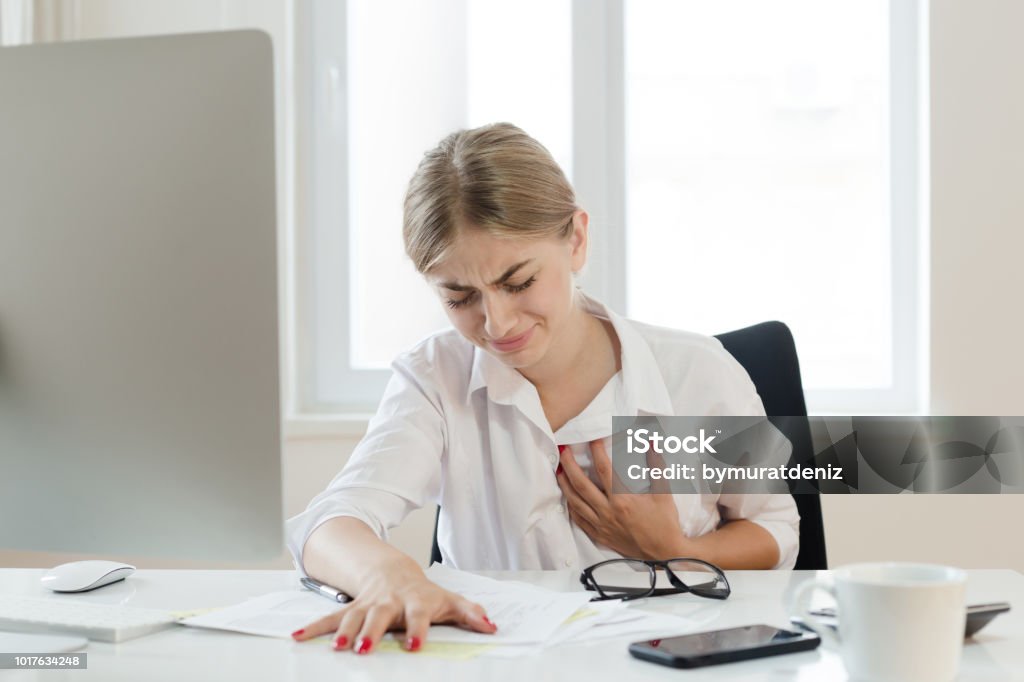 Young businesswoman touching her chest Heart Attack Stock Photo