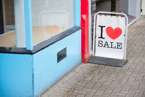 I love sale sign board on street pavement outside shop with love heart uk