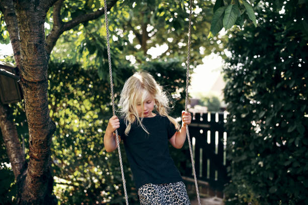 istock Cute little blonde girl playing on a tree swing outside 1017641724