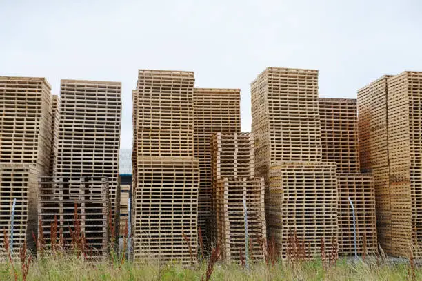 Stack of used wooden timber pallets for transportation of goods uk
