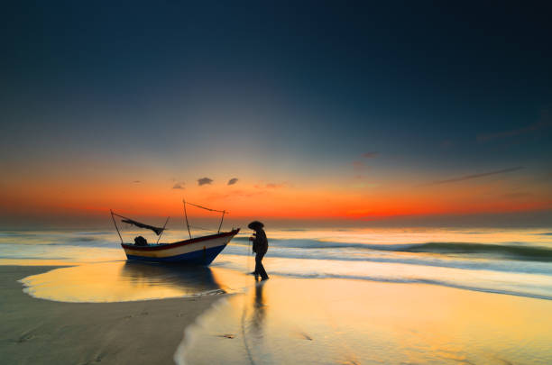 Silhoutte Malaysian fisherman try to pull boat to go to sea