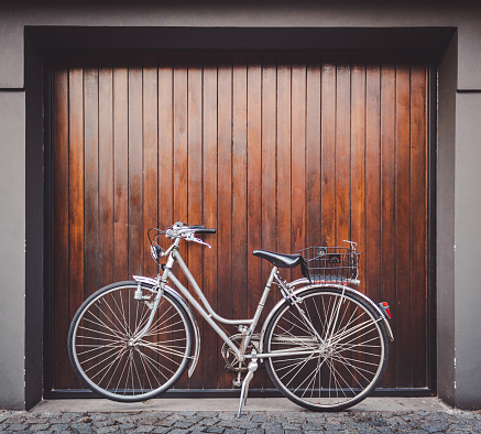 silver vintage bike parked inf front of a wood garage door