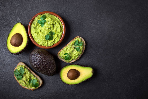 Mexican Dip Sauce Guacamole with avocado  in a clay bowl  on black background. Avocado spread. Top view. Copyspace"n Mexican Dip Sauce Guacamole with avocado  in a clay bowl  on black background. Avocado spread. Top view. Copyspace"n guacamole stock pictures, royalty-free photos & images