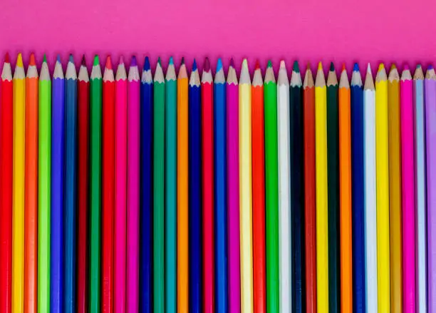 Photo of Seamless colored pensils  in a row  on pink  background. Close up. Education, school  concept.