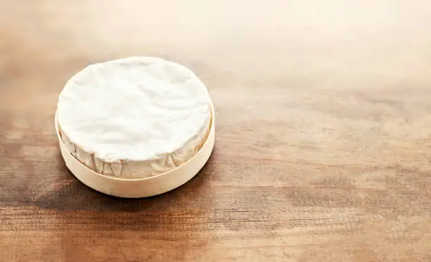 Cheese camembert on wooden desk, top view. Soft creamy cheese Brie with copy space"n