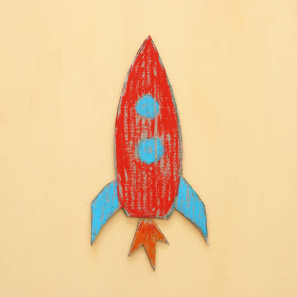 istock Rocket cut from cardboard and painted over wooden yellow background. 1017702592