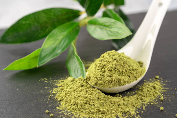istock Matcha powder in White ceramic spoon and tea leaves on black background 1017706320
