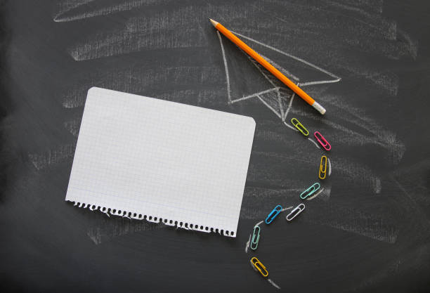 istock Top view image of plane sketch next to empty notebook paper over classroom blackboard background. 1017706846