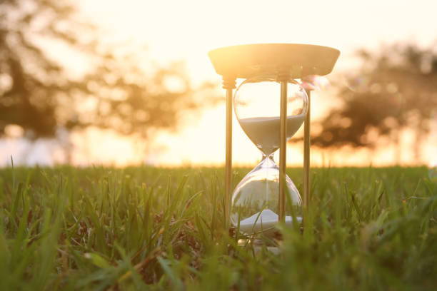 istock Hourglass in the grass time during sunset. vintage style. 1017707148