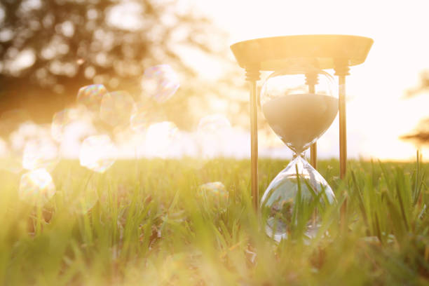 istock Hourglass in the grass time during sunset. vintage style. 1017707150