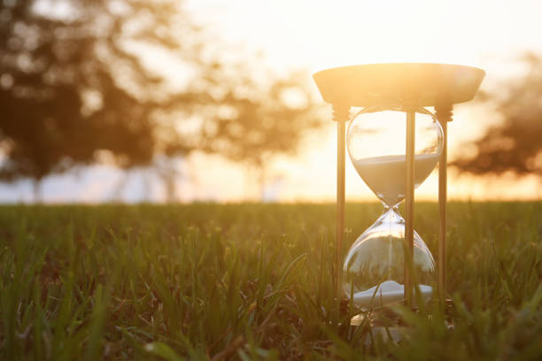 istock Hourglass in the grass time during sunset. vintage style. 1017707164