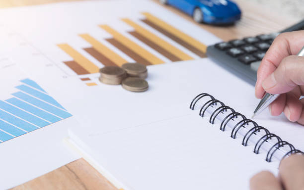 istock Businessman working and writing on notebook with stack of coins for financial and accounting concept. 1017709428