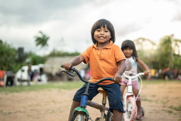 zwei kinder mit dem fahrrad in einem ländlichen ort - indian child stock-fotos und bilder