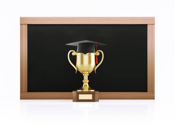 Golden trophy with a graduation cap in front of a blackboard on white background. Horizontal composition with copy space. Clipping path is included.