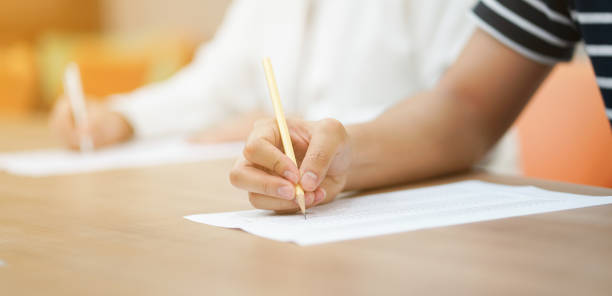istock close up student man hand choose answer on exam paper sheet after read book for next test scholarship concept 1017768776