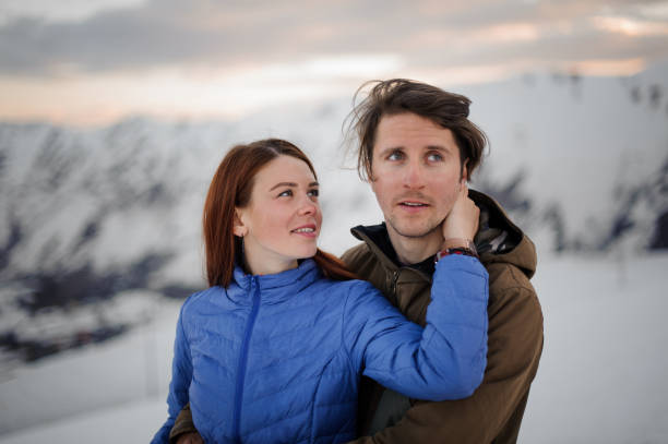 молодая пара, девушка и друг, восхищаются видом на снежные горы - affectionate desire beauty brown стоковые фото и изображения