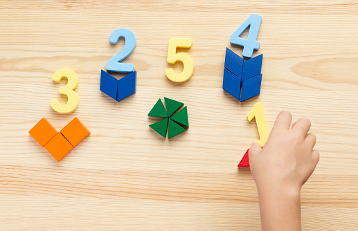 The child is studying the numbers and the account. Arranges the colored blocks to the desired numbers. Mathematics for children.
