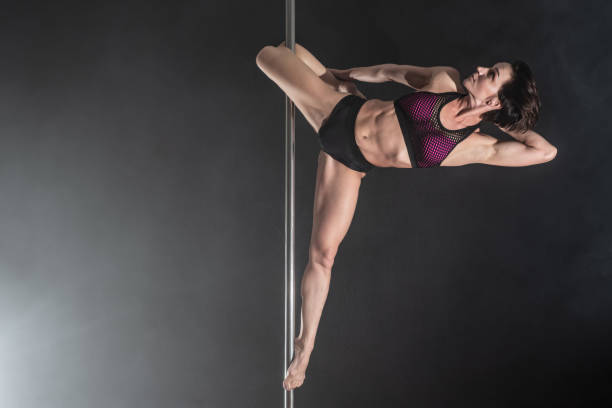 istock Beautiful slim girl with pylon. Female pole dancer dancing on a black background 1017779202