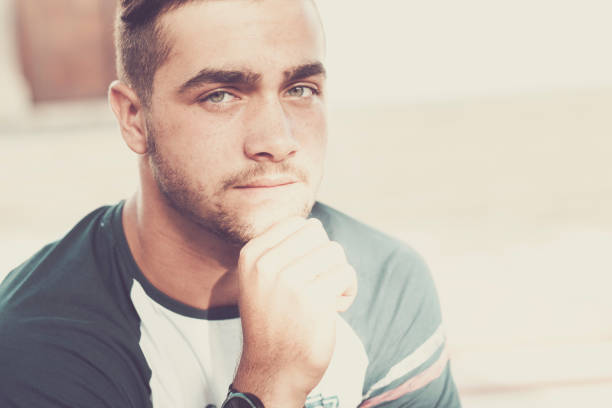 beautiful caucasian young boy looking at the camera directly and strong. nice expression for serious purposes. trendy and casual man with blue eyes. Vintage filter and retro colors