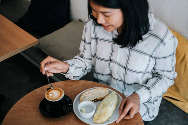 istock Asian woman having a omelette and coffee for breakfast at a cafe 1017793688