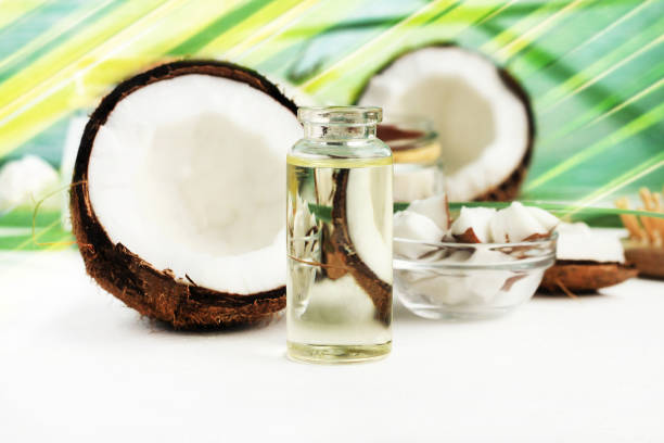 кокосовое масло в бутылке с открытыми орехами и мякотью в банке, зеленый фон пальмового листа. - facial mask herbal medicine spa treatment ayurveda стоковые фото и изображения
