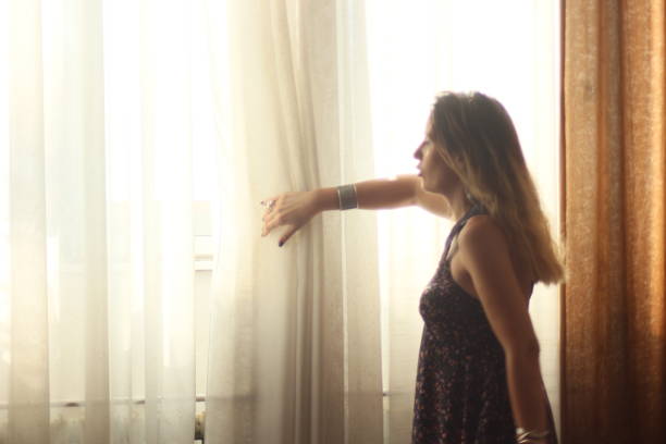 istock Woman arranging curtains 1017830160