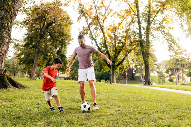 Father teaches son how to play football