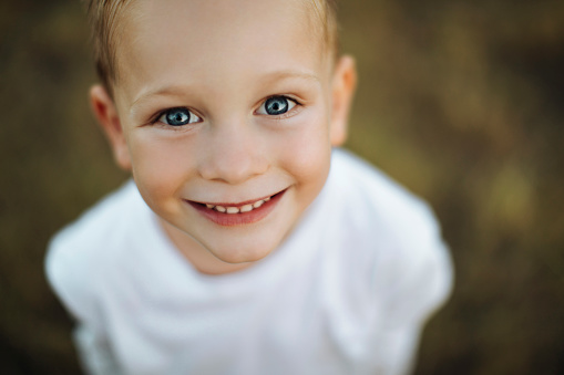 Close up portrait of a cute little boy smiling at the camera outdoors