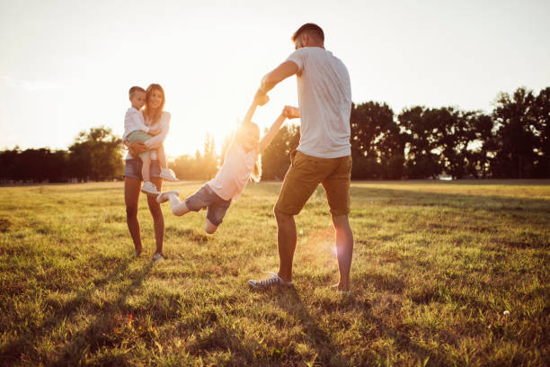 Carefree childhood Young couple having fun with their two kids in the beautiful park at summer natural parkland stock pictures, royalty-free photos & images