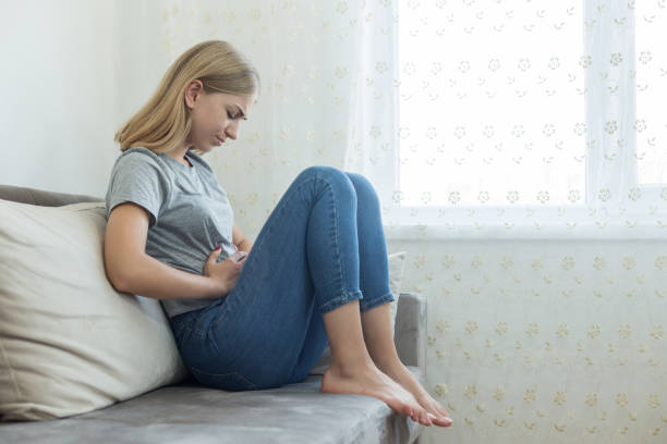 Young woman sitting on sofa and touching her stomach. Young woman sitting on sofa and touching her stomach. Stomach Cramps and Diarrhea stock pictures, royalty-free photos & images