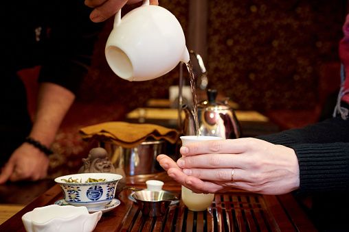 Tea ceremony. A girl holding a tea cup in which hot tea is poured
