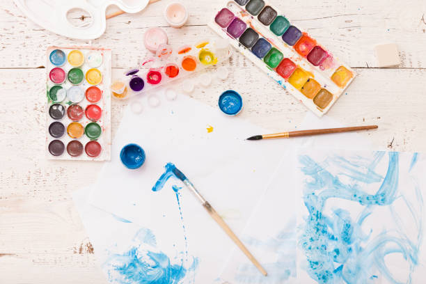 istock Top view on child's drawings and colorful paints and brushes. Creative ideas, creativity and early learning. Education concept. 1017874720
