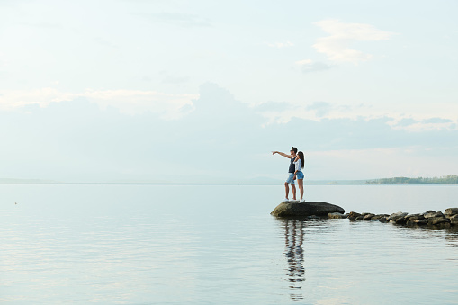 Young couple standing on pier and looking at the lake