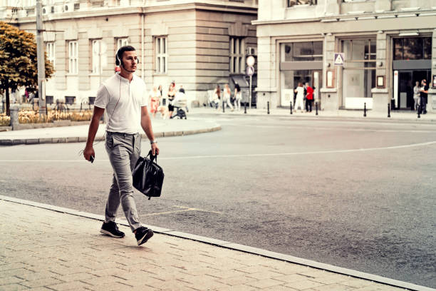 elegant stylish man walking on the street outside with briefcase in his hand on way to work