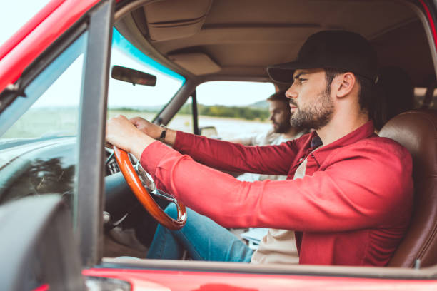 istock side view of serious young men riding car in field 1017887932