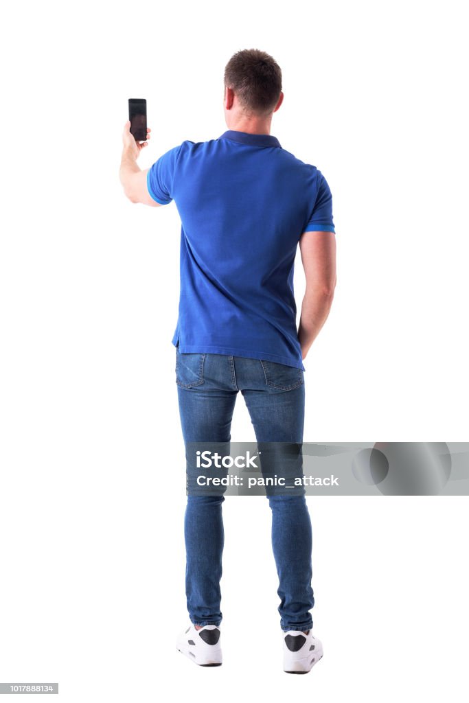 Rear view of modern adult casual man taking photo with smart phone. Rear view of modern adult casual man taking photo with smart phone. Full body isolated on white background. Rear View Stock Photo